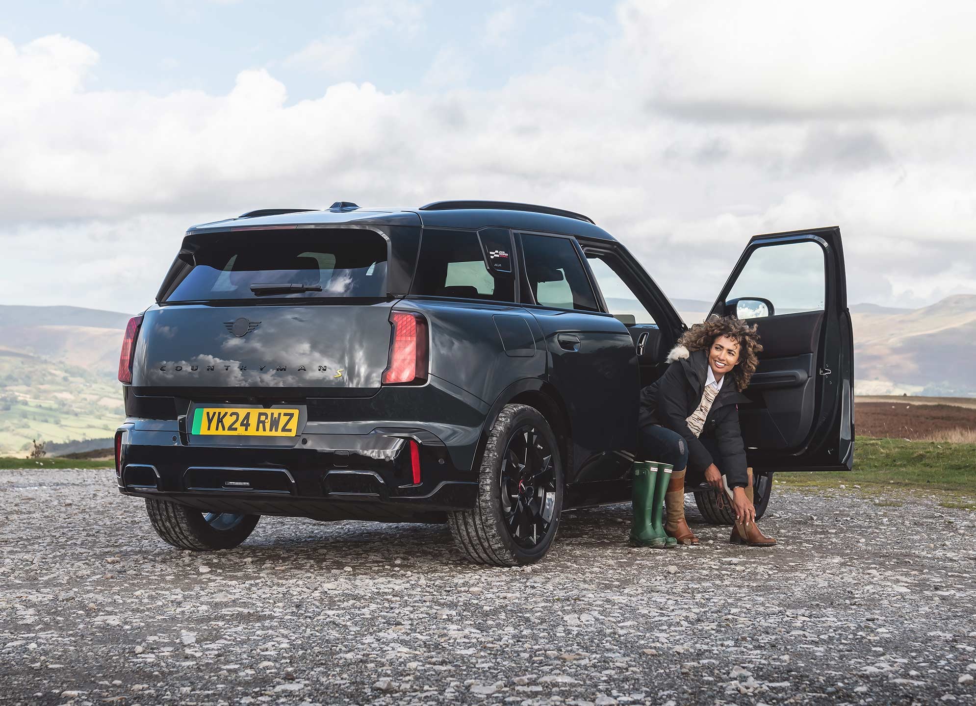 Rear view of the all-electric MINI Countryman in Smokey Green and Vibrant Silver roof parking. 